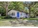 Charming single-story home with a blue front door, surrounded by lush trees and a well-maintained lawn at 10565 Bessemer St, New Port Richey, FL 34654