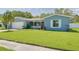 Attractive one-story home featuring a well-manicured lawn, large driveway, and beautiful shrubs at 1101 Mclean St, Dunedin, FL 34698