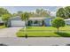 Charming blue single-story home with well-maintained landscaping, lush lawn, and a spacious two-car garage at 1101 Mclean St, Dunedin, FL 34698