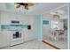 Bright kitchen with white appliances, white cabinetry, and light blue accent walls open to the dining area at 1101 Mclean St, Dunedin, FL 34698