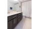Bathroom featuring a double sink vanity with dark cabinets, neutral tile flooring, and bathtub with shower at 11109 Carrick Stone St, Wimauma, FL 33598