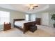 Spacious bedroom featuring neutral paint, carpet, tray ceiling, a dark wood bed, and side tables at 11109 Carrick Stone St, Wimauma, FL 33598