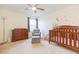 Well-lit Bedroom featuring a wooden crib, changing table, soft chair, and decorative wall art at 11109 Carrick Stone St, Wimauma, FL 33598