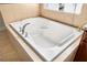 A close-up of a pristine, large white bathtub with chrome fixtures and neutral tiled surround is featured at 11845 Newberry Grove Loop, Riverview, FL 33579