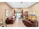 Cozy living room with dark leather furniture, tile flooring, and natural light from sliding glass doors at 11845 Newberry Grove Loop, Riverview, FL 33579