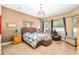 Inviting main bedroom with a woven bed frame, tiled floor, and two bright windows at 11845 Newberry Grove Loop, Riverview, FL 33579