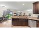 Open kitchen with granite countertops, dark cabinets, and a view into the living room and backyard at 11871 Crestridge Loop, Trinity, FL 34655