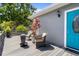 Cozy backyard deck featuring comfortable wicker seating, potted plants, and a stylish turquoise front door at 1209 W Adalee St, Tampa, FL 33603