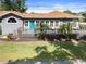 Charming home featuring a cozy front deck, blue entry door, and well-maintained lawn at 1209 W Adalee St, Tampa, FL 33603
