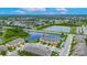 Scenic aerial view of townhomes beside a serene lake, complemented by lush greenery and a clear blue sky at 12952 Utopia Gardens Way, Riverview, FL 33579