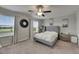 Bedroom with large windows, a ceiling fan, nightstands, art and a large gray bed at 12952 Utopia Gardens Way, Riverview, FL 33579