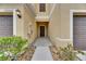 A covered entryway with a brown front door, small landscaping, and house numbers at 12952 Utopia Gardens Way, Riverview, FL 33579