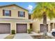 A townhome with brown shutters, a garage and a well manicured green lawn with a palm tree at 12952 Utopia Gardens Way, Riverview, FL 33579