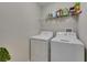 Clean laundry room includes a washing machine, dryer and shelving for storage of supplies at 12952 Utopia Gardens Way, Riverview, FL 33579