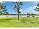 A picturesque view of a serene pond framed by lush green grass and scattered trees, on a sunny day at 12952 Utopia Gardens Way, Riverview, FL 33579
