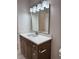 Bathroom vanity featuring a sink, chrome fixtures, wood cabinets, decorative mirror, and lighting at 13532 14Th St, Dade City, FL 33525