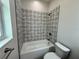 Bright bathroom featuring a tub with decorative tile surround, a window, and a toilet at 13532 14Th St, Dade City, FL 33525