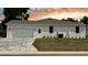 View of exterior showcasing attached two car garage, white stucco, a neatly maintained lawn and interlocking brick driveway at 13532 14Th St, Dade City, FL 33525