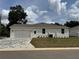 View of exterior showcasing attached two car garage, white stucco, a neatly maintained lawn and interlocking brick driveway at 13532 14Th St, Dade City, FL 33525