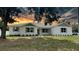 Charming single story home featuring a brick facade, dark green shutters, manicured landscaping and a warm sunset sky at 13532 14Th St, Dade City, FL 33525