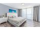 Bright bedroom with wood-look floors, white furniture, and ocean art at 1390 Gulf Blvd # Ph-5, Clearwater, FL 33767