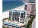 Exterior view of a beachfront condo building with a pool, tennis court, and covered parking at 1390 Gulf Blvd # Ph-5, Clearwater, FL 33767