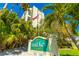 Sand Key Club Condo community sign with tropical landscaping, an American flag, and the building in the background at 1390 Gulf Blvd # Ph-5, Clearwater, FL 33767