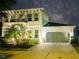 Well-lit two-story home under a starry sky, featuring a wide driveway and manicured landscaping at 15422 Starling Crossing Dr, Lithia, FL 33547