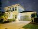 Beautifully lit two-story home with a gray two-car garage, sidewalk, and neat front yard landscaping at night at 15422 Starling Crossing Dr, Lithia, FL 33547