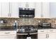 Gas range with granite counters and a stylish backsplash at 15422 Starling Crossing Dr, Lithia, FL 33547