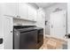 Well-lit laundry room features white cabinets, tile floor, and new black washing machine at 15422 Starling Crossing Dr, Lithia, FL 33547