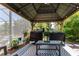 Outdoor gazebo with a peaked roof covering a seating area and two grilling stations near a pool and foliage at 15422 Starling Crossing Dr, Lithia, FL 33547