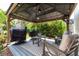 Outdoor gazebo with a peaked roof covering a seating area and two grilling stations in a peaceful garden setting at 15422 Starling Crossing Dr, Lithia, FL 33547