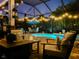 Tranquil screened-in pool area illuminated by string lights and lush landscaping at 15422 Starling Crossing Dr, Lithia, FL 33547