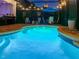 An in-ground pool at night featuring string lights and an umbrella with chairs for relaxing poolside at 15422 Starling Crossing Dr, Lithia, FL 33547