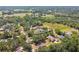 Picturesque aerial view of a neighborhood with homes surrounded by mature trees, near lush green fields and shimmering lakes at 18902 Spring Hollow Dr, Lutz, FL 33559