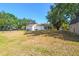 View of the backyard showing the back of the house, storage shed and fenced yard on a sunny day at 18902 Spring Hollow Dr, Lutz, FL 33559