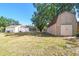 Rear view of a home with a storage shed, fenced yard and large backyard with mature shade trees at 18902 Spring Hollow Dr, Lutz, FL 33559