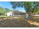View of the house with long screened lanai and a fenced backyard with mature trees and a play structure at 18902 Spring Hollow Dr, Lutz, FL 33559