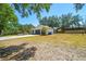 Wide angle shot of a well-maintained property featuring lush grass, mature trees, and a convenient two-car garage at 18902 Spring Hollow Dr, Lutz, FL 33559