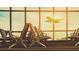Sunlit airport terminal with rows of chairs facing a window view of an airplane taking off at 1915 W Del Webb Blvd, Sun City Center, FL 33573