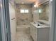 Cozy bathroom featuring marble-tiled floors and walls, with a combined shower and tub at 209 Rosery Rd, Belleair, FL 33756