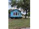 Charming light blue home with a red roof, white trim, and mature trees in a peaceful neighborhood at 21034 Lirio Dr, Land O Lakes, FL 34637