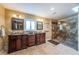 Bathroom featuring double sink vanities, a walk-in shower, decorative mirrors, and travertine floors at 2834 Pelham N Rd, St Petersburg, FL 33710