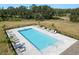 Aerial view of a community pool with lounge chairs and mature landscaping at 34847 Daisy Meadow Loop, Zephyrhills, FL 33541