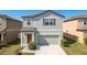 Charming two-story home featuring a gray facade, attached garage and well-maintained landscaping at 34855 Daisy Meadow Loop, Zephyrhills, FL 33541