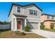 Charming two-story home featuring a gray facade, attached garage and well-maintained landscaping at 34855 Daisy Meadow Loop, Zephyrhills, FL 33541