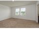 Bright bedroom featuring plush carpet, two windows, and neutral paint providing natural light at 34866 Daisy Meadow Loop, Zephyrhills, FL 33541