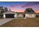 Charming single-story home with a modern white exterior and a well-manicured lawn under a colorful sunset at 3707 Orangepointe Rd, Valrico, FL 33596