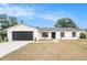 Charming single-story home with a modern white exterior, black trim and garage door, and a well-manicured lawn at 3707 Orangepointe Rd, Valrico, FL 33596